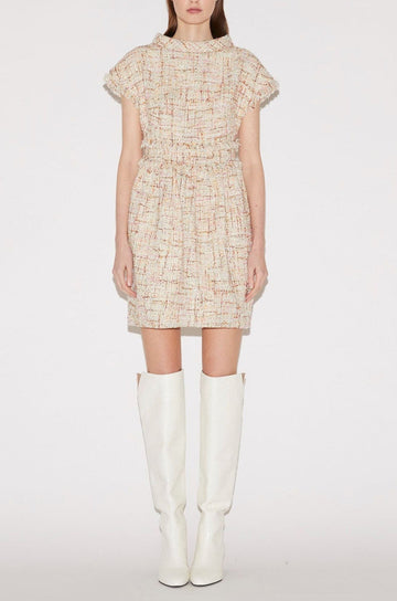 A model stands against a light gray studio background wearing a short cream tweed dress with a high collar and ruffled cap sleeves, paired with tall white boots.